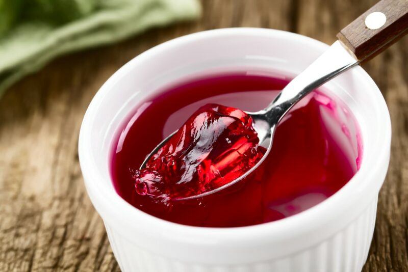 A white dish containing red jello with a spoon