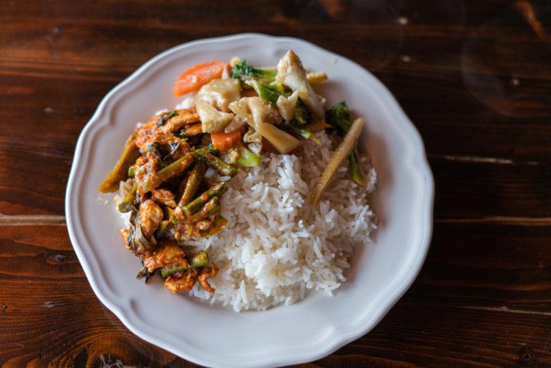 A white dish containin khao rad gaeng, which is basically a type of curry with rice