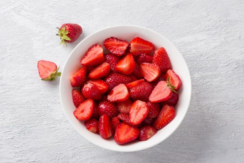 A white bowl filled with sliced fresh strawberries