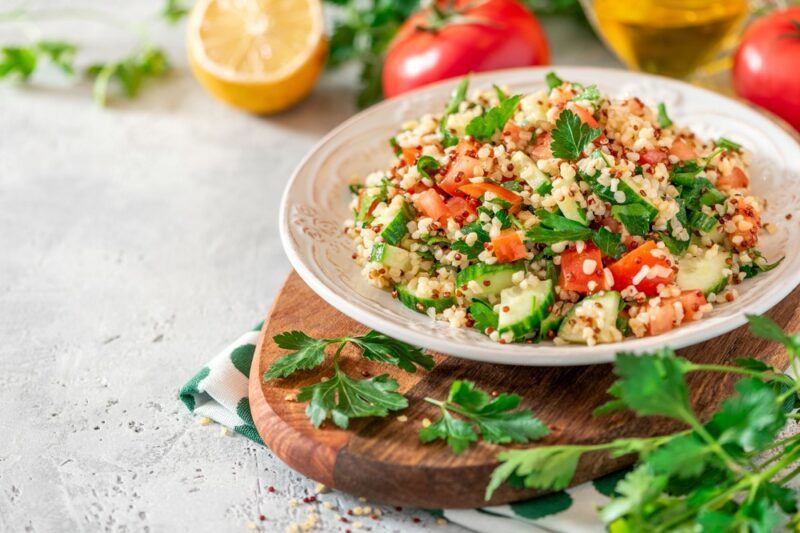 A bowl of tabbouleh salad with fresh tomatoes and parsley on the top