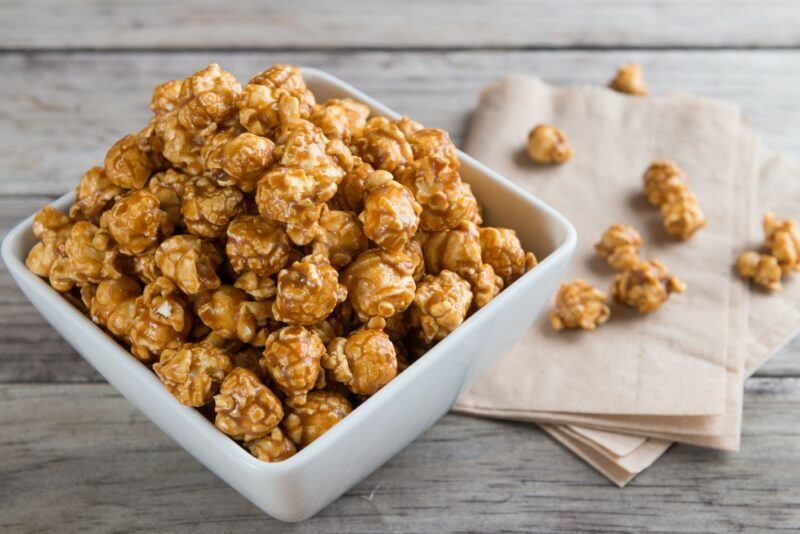 A white square bowl with Kentucky salted bourbon popcorn. There is also a cloth with a few more pieces of popcorn.