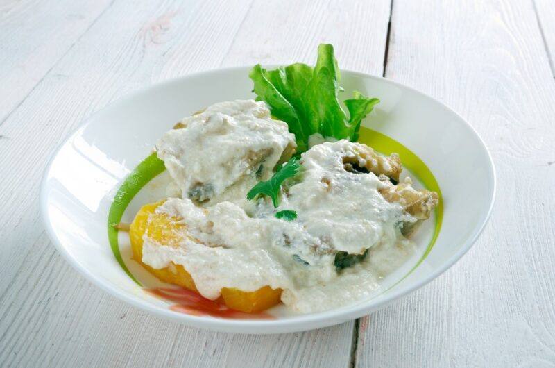 A white bowl with a meal called run down that's covered in some type of cream or white sauce