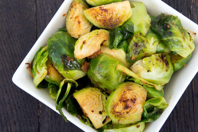 A white bowl with cooked Brussels sprouts and bacon