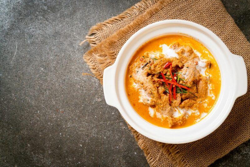 A white dish on a brown sack, where the dish contains a bright orange curry