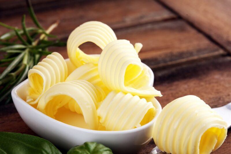 A small white dish with swirls of margarine on a wooden table