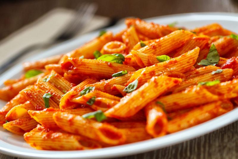 A white plate with pasta in a red sauce