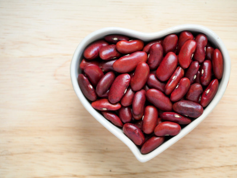 A white bowl shaped like a heart that is full of kidney beans