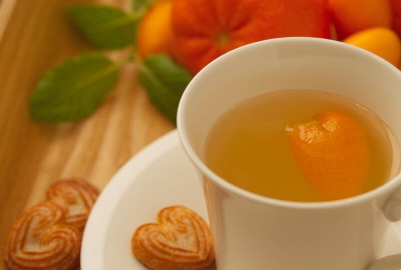 A white saucer with a white mug that contains kumquat tea