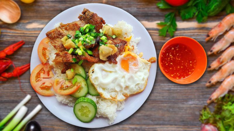 A white plate with a broken rice dinner that includes various fresh ingredients