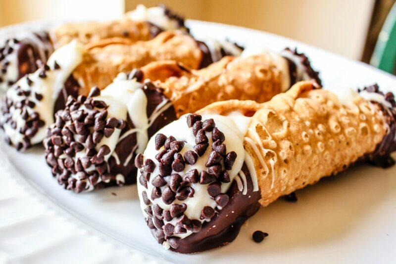 A white plate with Italian cannoli that has been dipped in chocolate and has chocolate chips