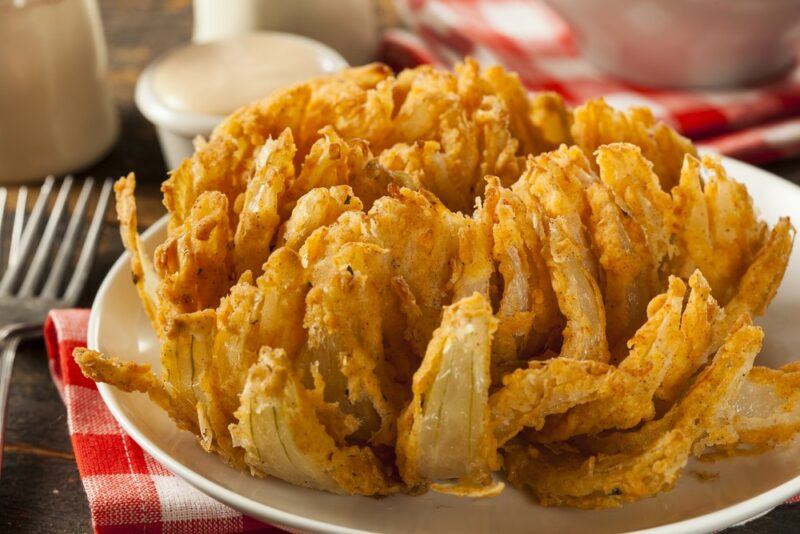 A white plate containing a bloomin' onion on a checkered tablecloth