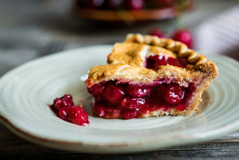 A white plate with a single slice of cherry pie