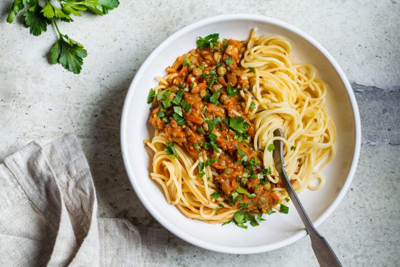 A white dish with cooked pasta noodles and a lentil-based sauce