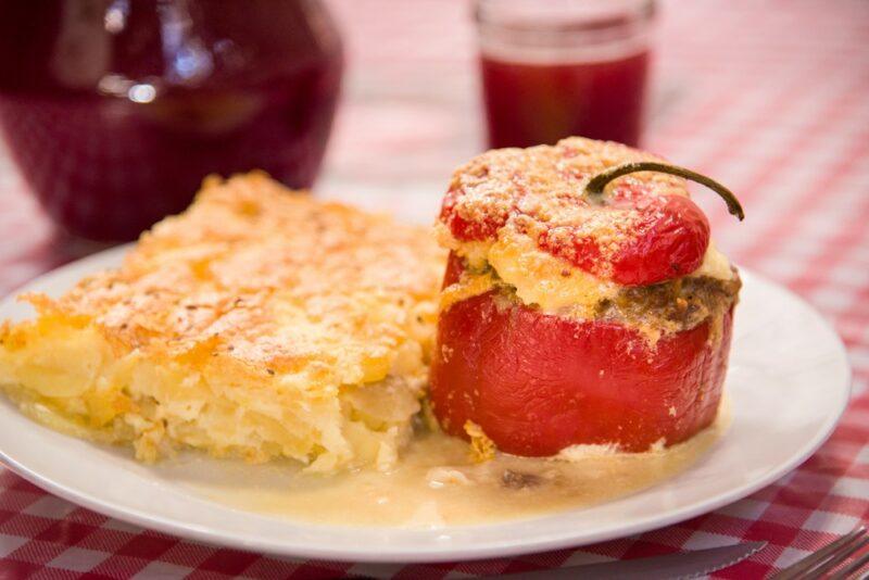 A white dish with a stuffed red pepper called rocoto relleno, next to some type of potato dish