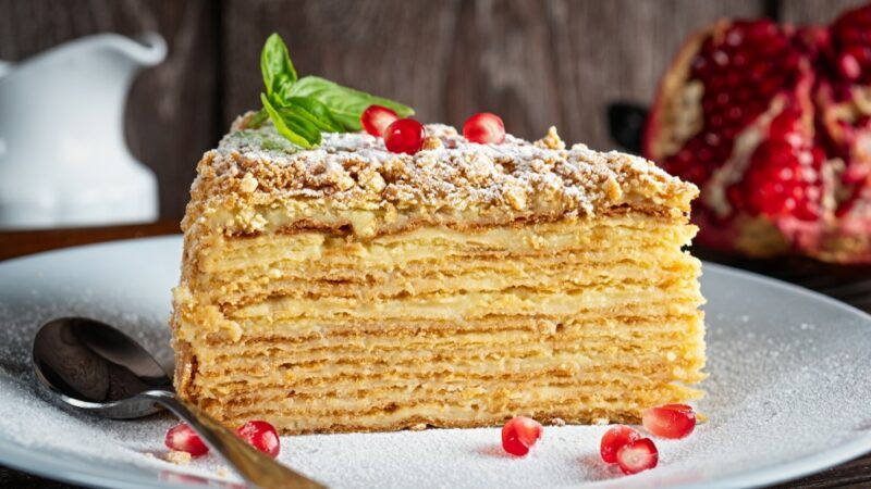 A white plate with a stacked piece of Napoleon cake