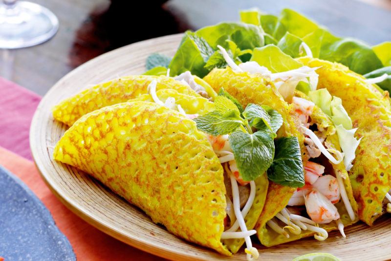 A white plate with banh xeo shells that are stuffed with fillings