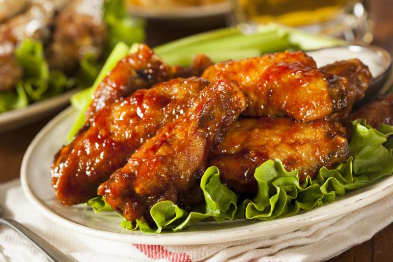 A white plate with buffalo wings and some lettuce