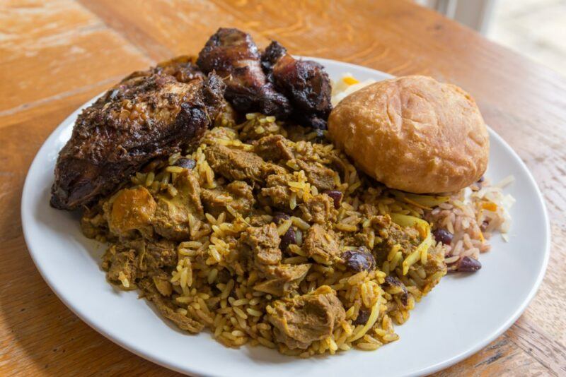 A white plate with a goat curry and some type of bread or dumpling