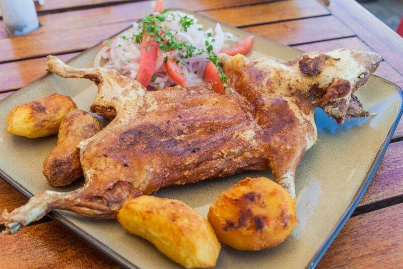 A square plate or board with cooked cuy and potatoes