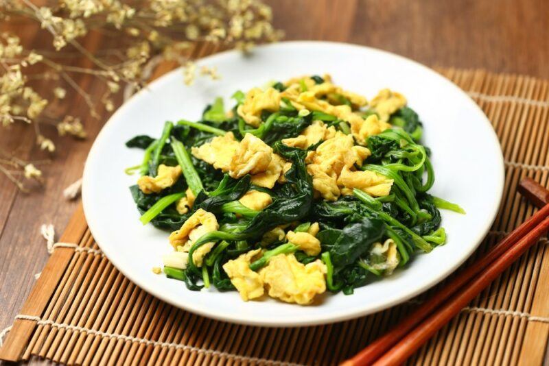 A white plate with a dish of scrambled eggs and spinach - an easy source of protein and nutrients