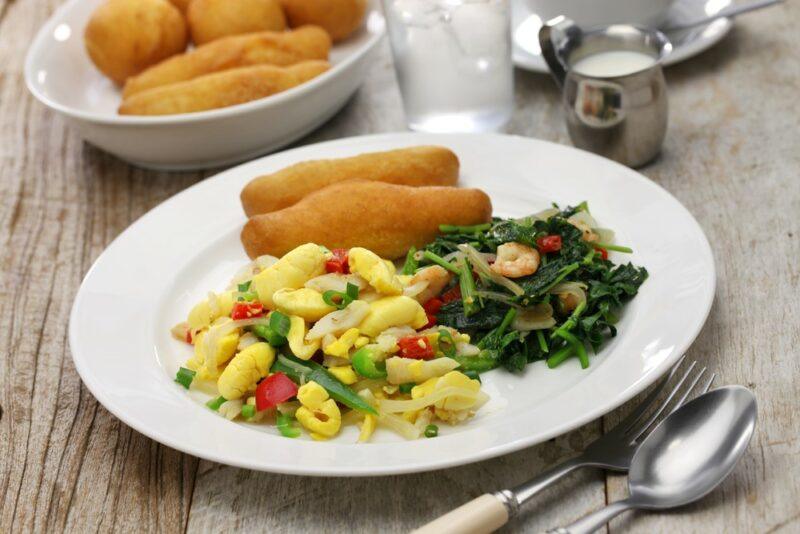 A white plate with three Jamaican dishes, including cod, callaloo and festivals