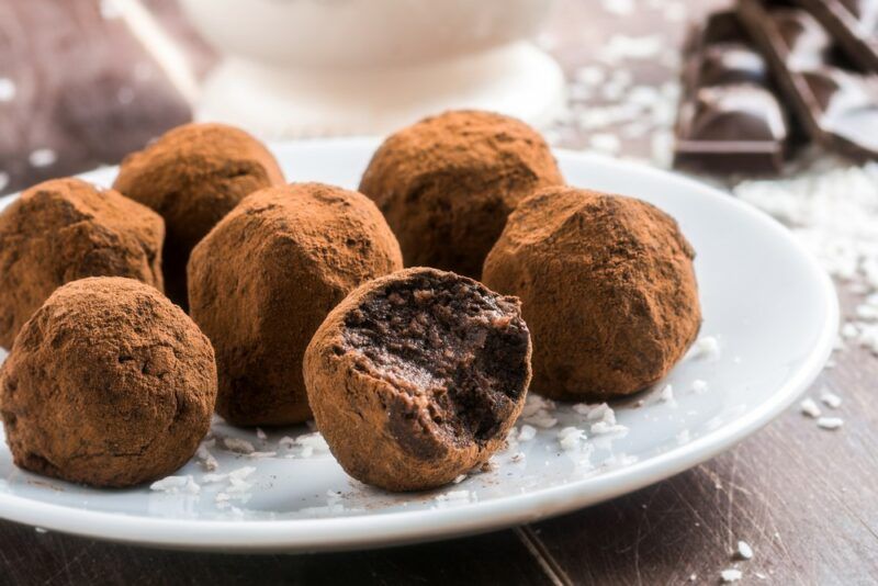 A white plate with a selection of keto chocolate truffles that have been rolled in cocoa powder