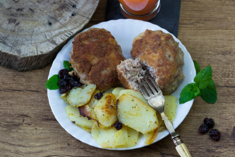 A white plate with kotlet mielony next to a fork