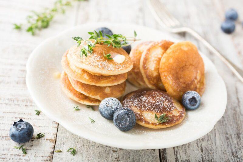 A white plate with small pancakes and blueberries