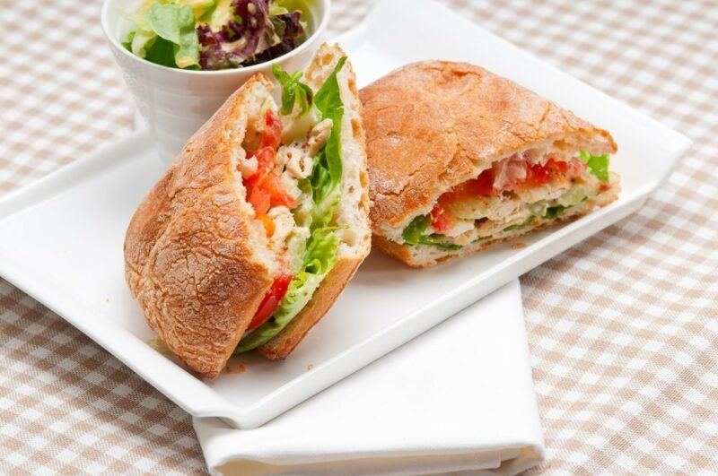 A white plate with two delicious ciabatta sandwiches, perfect for a picnic