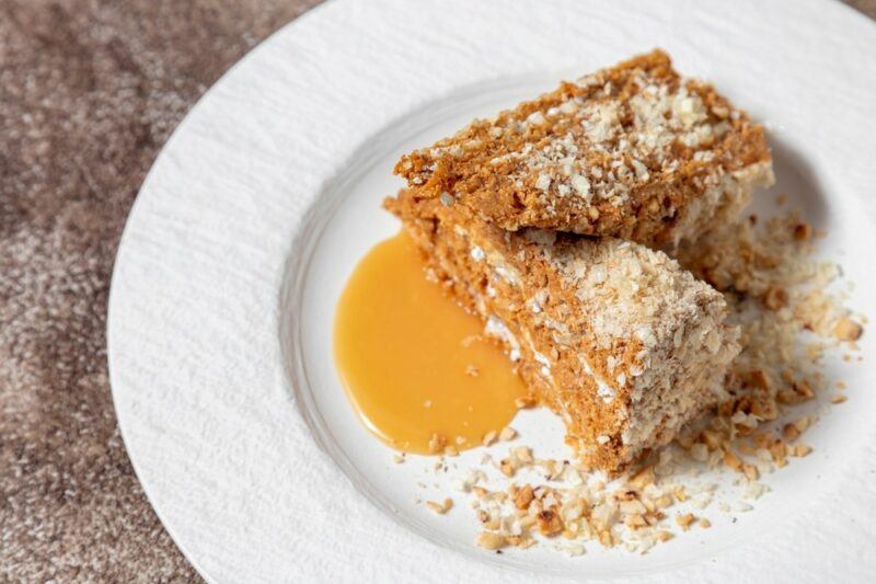 A white plate with two layered waffle cakes, next to a small puddle of sauce