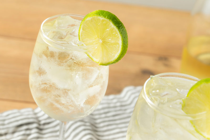 Two glasses of white wine spritzer with a piece of lime as a garnish