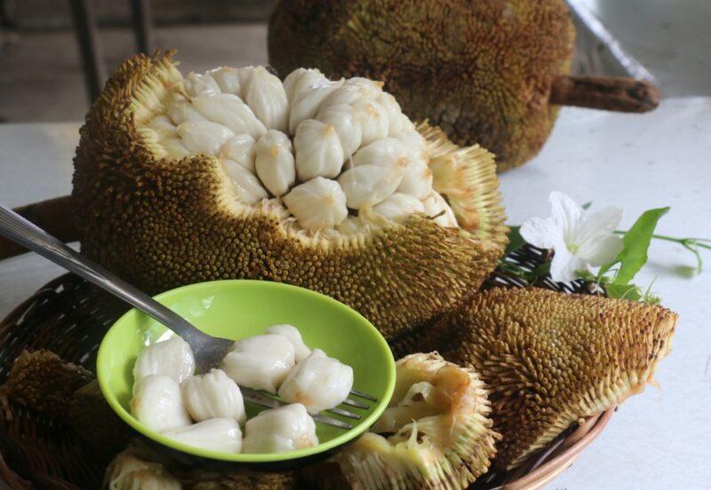 A plate with most of a marang fruit, next to a small green bowl containing marang flesh