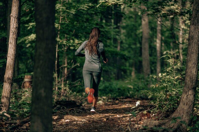 A woman with brown hair running through a forest