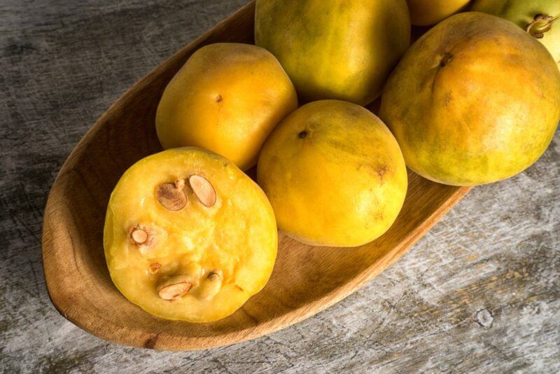 A wooden board with five araza fruits, one that has been cut in half