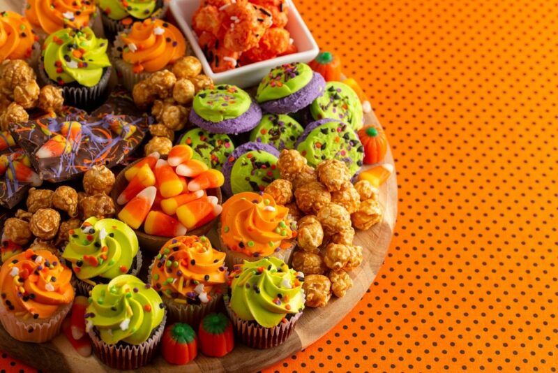 A board containing Halloween treats, including cupcakes and candy