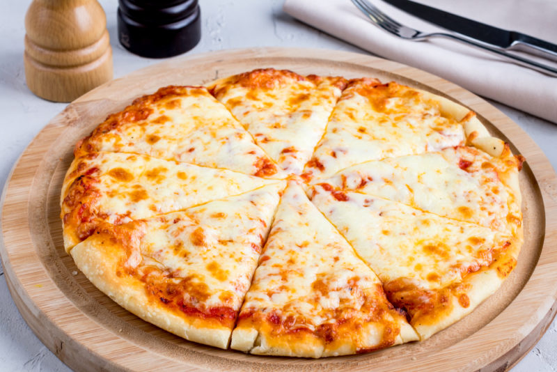 A wooden board with a cheese pizza | Food For Net A wooden tray that contains a sliced cheese pizza