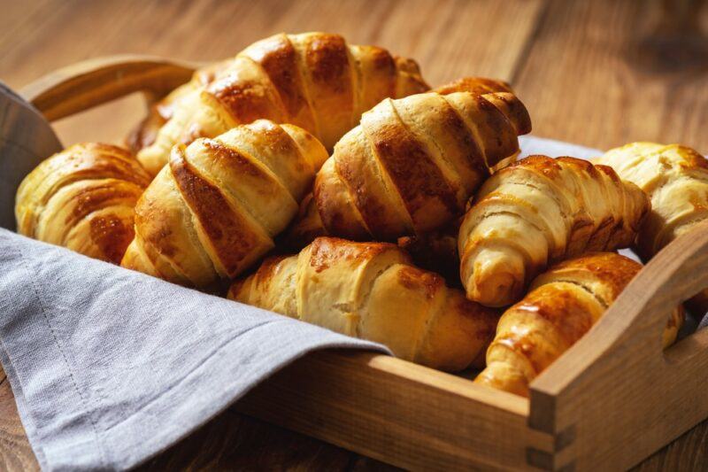 A wooden tray containing small croissants