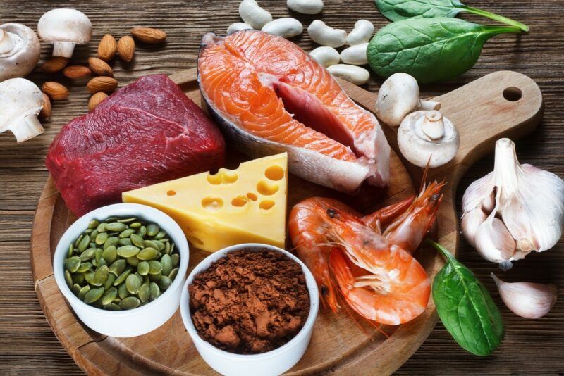 A wooden board with raw meat and other zinc rich foods