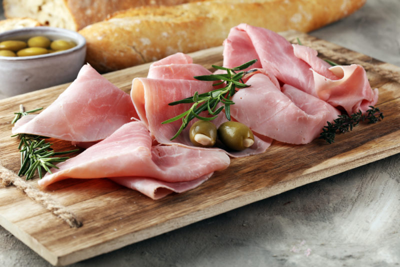 A wooden board with pieces of sliced ham