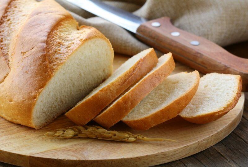 A wooden board with sliced bread and a knife