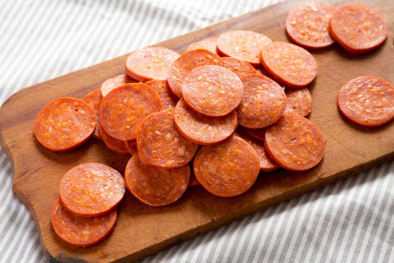 A wooden board with slices of pepperoni