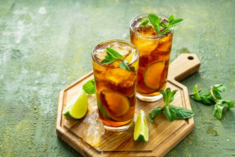 Two glasses of sparkling iced tea on a wooden board with some limes