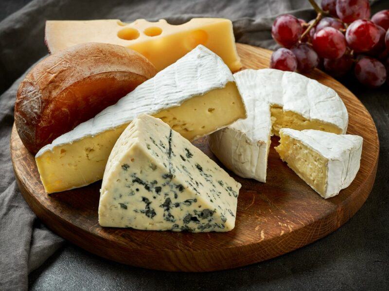 A wooden board with a selection of fresh cheeses