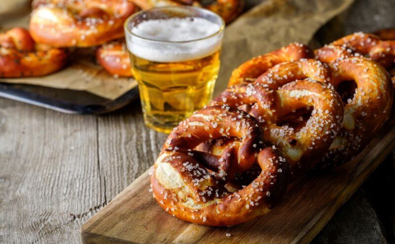 A wooden table with plenty of fresh pretzels and a glass of beer