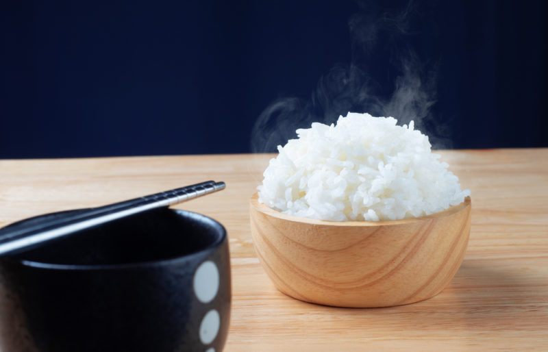 A wooden bowl of cooked rice | Food For Net A small wooden bowl of cooked rice in front of a black bowl with chopsticks