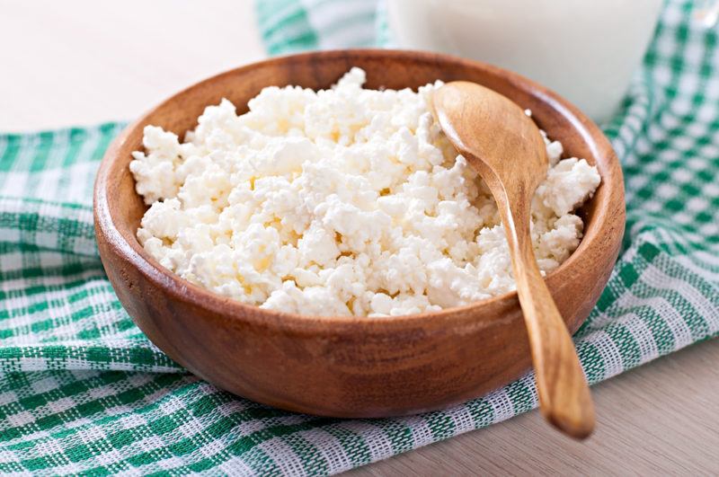 A wooden bowl of cottage cheese with a napkin