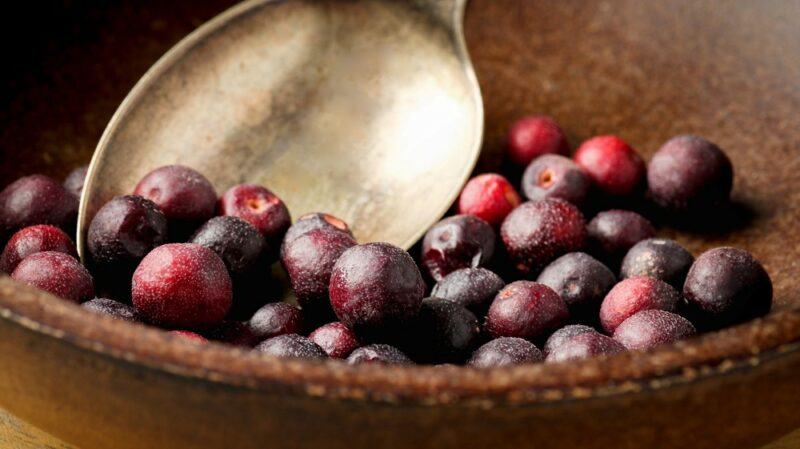 A basket filled with phalsa berries and a metal spoon