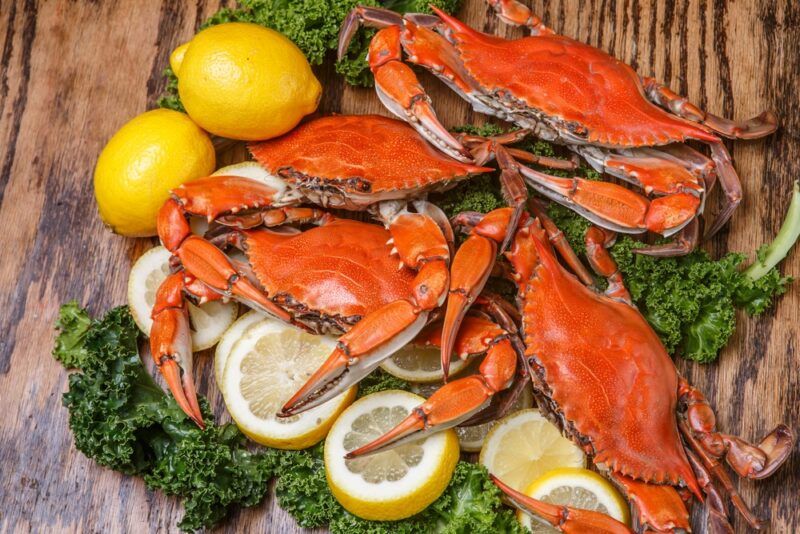 A wooden table with various fresh crabs and lemons