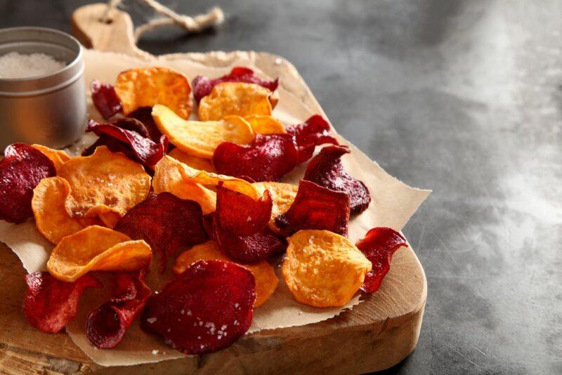 A thick wooden slab with cooked veggie chips