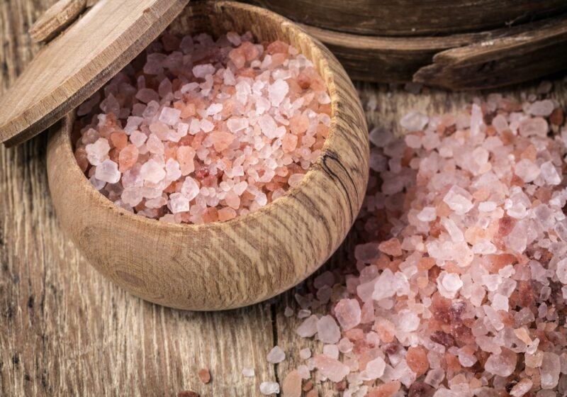 A wooden table with a pile of sea salt and a wooden dish containing more sea salt